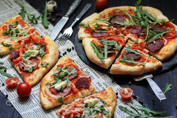 Italian cuisine concept, pizza pepperoni with sausage and arugula on a dark wooden background