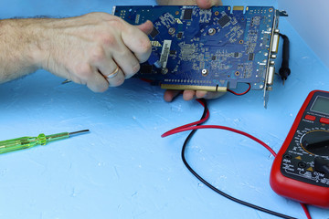 Male hands repair an electronic device using Multimetr, measuring the voltage of the computer...
