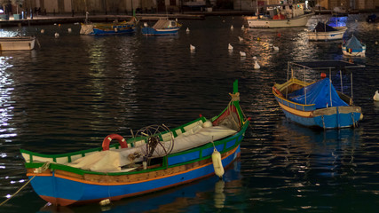 Fototapeta na wymiar Colorful boats on the water of mediterranean sea bay in Malta at dark night with artificial lights
