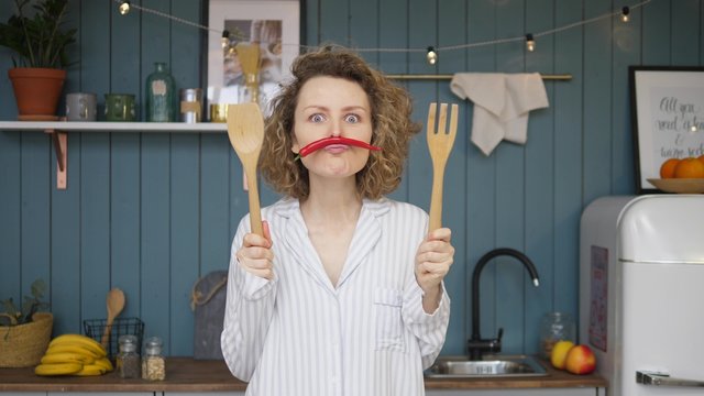Portrait Of Funny Young Woman With Moustache From Chili Pepper In Kitchen