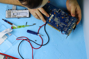 Male hands repair an electronic device using Multimetr, measuring the voltage of the computer...