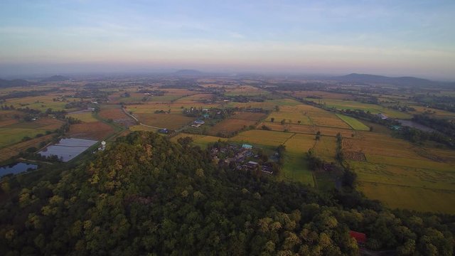 VDO. Aerial view of top hill and buddhist temple with rice paddy fields and cloudy sky background, Wat Khao Chong Pran, Photharam, Ratchaburi, west of Thailand.