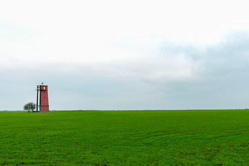 Fototapeta na wymiar Old lighthouse with red stripes. Scenic landscape with a tall lighthouse.