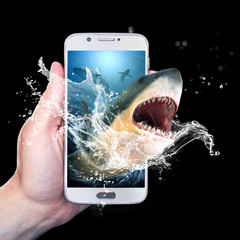Hand holding a smartphone with a shark coming out of it