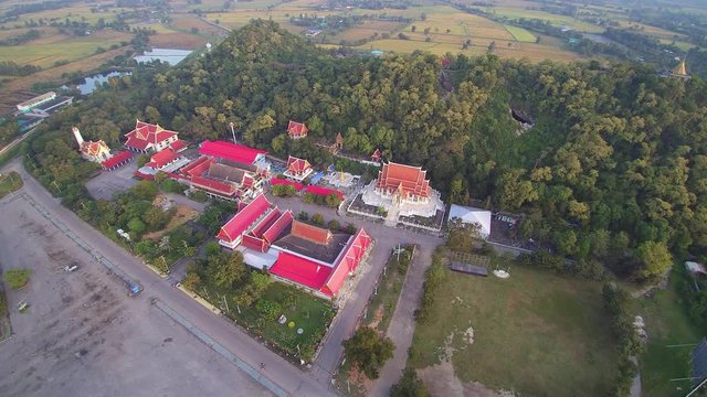 VDO. Aerial view above Buddhist Temple with green hill background, Wat Khao Chong Pran or Bat Temple in Photharam District, Ratchaburi, west of Thailand.