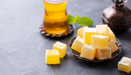 Turkish delight on a copper plate with glass of tea. Grey stone background. Copy space.