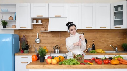 Woman Listening Music Wearing Headphones And Dancing On Kitchen While Cooking.