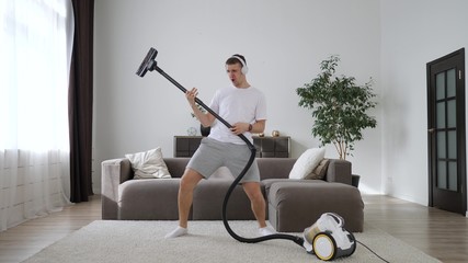 Young Funny Man Dancing With Vacuum Cleaner Playing Guitar