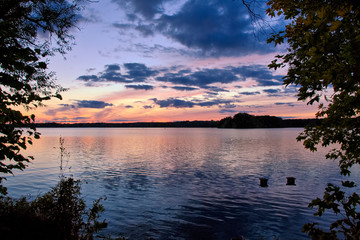 View of the lake at sunset with picturesque play of colors, silhouettes and a peaceful atmosphere.