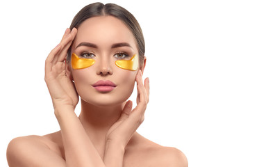 Woman with under eye collagen gold pads, beauty model girl face with healthy fresh skin. Skin care concept, anti-aging moisturizing eye mask, golden hydrogel patches, eye skin treatment, cosmetology