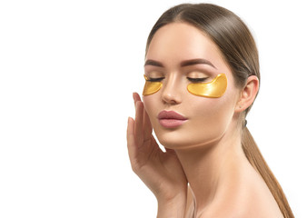 Woman with under eye collagen gold pads, beauty model girl face with healthy fresh skin. Skin care concept, anti-aging moisturizing eye mask, golden hydrogel patches, eye skin treatment, cosmetology