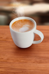 café con leche caliente en taza de porcelana sobre mesa de madera. hot latte coffee in porcelain cup on wooden table.