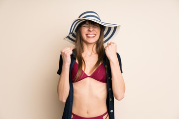 Woman in bikini on ocher background celebrating a victory