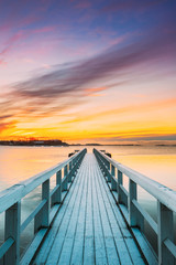 Old Frosted Wooden Boards Pier On Calm Water Of Lake Or River Or Sea At Evening Or Morning Time. Sunset Sunrise In Winter Season