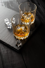 glass of whiskey and ice on wooden table