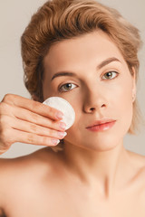 beautiful woman with short blond hair wipes her face with a cotton pad. Skin care concept