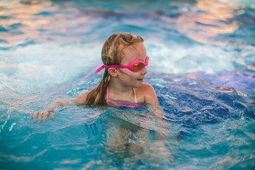 Little girl playing and swimming on the pool 