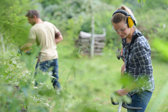 man and woman strimming long grass