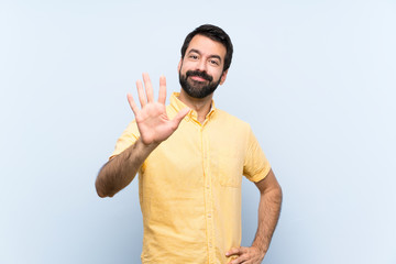 Naklejka premium Young man with beard over isolated blue background counting five with fingers