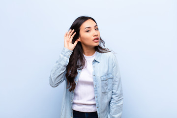 young latin pretty woman looking serious and curious, listening, trying to hear a secret...