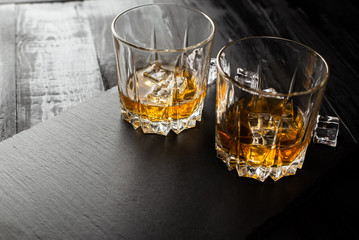 glass of whiskey and ice on black background