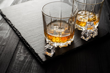 glass of whiskey and ice on black background