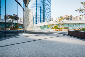 empty footpath with modern office building exterior and blue clo