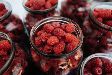 Fresh, ripe raspberries in small jars close-up