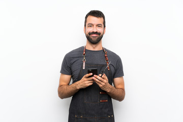 Barber man in an apron sending a message with the mobile