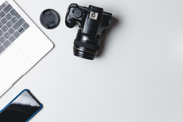Photographer's workplace on a white background. Modern laptop, digital camera, lens, battery, smartphone. Minimalism. Top view. Copy space. Equipment for the photographer. The concept of freelancing