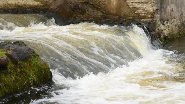 Close up of river stream flowing down over the grey stones. Stock footage. Fast and cold brook with clear water flowing during spring time.