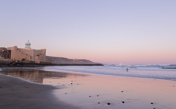 Surfer going to the water in Las Canteras beach, la cicer at sunrise in Las Palmas de Gran Canaria, Canary islands, Spain.  Surfing in Gran Canaria concept.