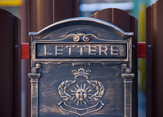 vintage retro metal brown mailbox with the inscription "Lettere" hanging on the iron fence. antique style