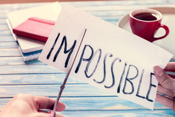 Inscription on paper "impossible" which is cutting by scissors