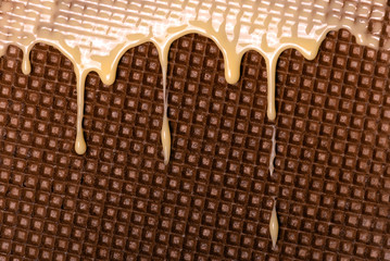 Waffle covered with condensed milk close-up. White hot chocolate spreads on the wafer. Tasty food