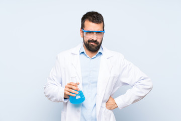 Young scientific holding laboratory flask over isolated background angry