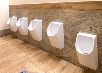 White urinals in men's bathroom, the design of white ceramic urinals for men in the toilet room....
