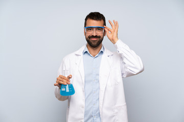 Young scientific holding laboratory flask over isolated background with glasses and happy
