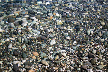 Sea stones in sea water. Pebbles under water. The view from the top. Nautical background. Clean sea water. Transparent sea