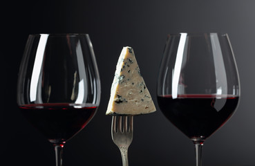 Piece of blue cheese on a fork and red wine.