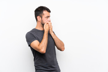 Young handsome man over isolated white background covering mouth and looking to the side