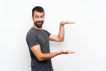 Young handsome man over isolated white background holding copyspace to insert an ad