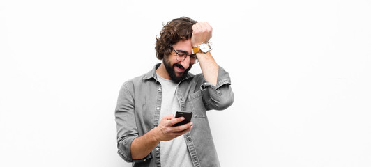 young crazy cool man using his smartphone against white wall
