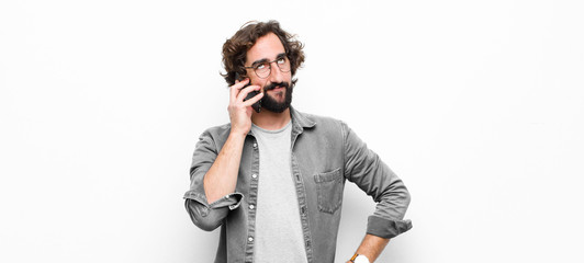 young crazy cool man using his smartphone against white wall