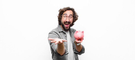 young crazy cool man holding a piggy bank against white wall