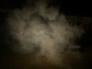 Wasserdampf beim Abloeschen eines Lagerfeuers in einer grossen Feuerschale