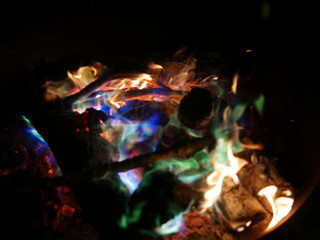 Feuer in grosser Feuerschale mit gelben, gruenen und blauen Flammen und roter Glut