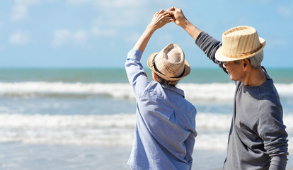 Asian senior couple elder retire resting relax walking at sunrise beach honeymoon.Happy family together people lifestyle