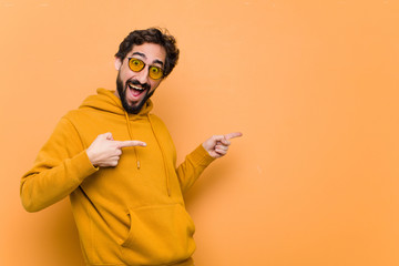 young crazy cool man pointing to the side against orange wall