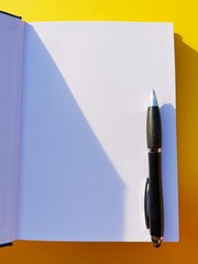 notebook, pen, on yellow background.  top view copy space